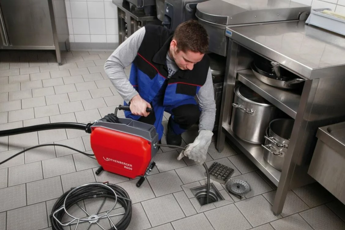 Técnico desentupidor desentupindo ralo com máquina