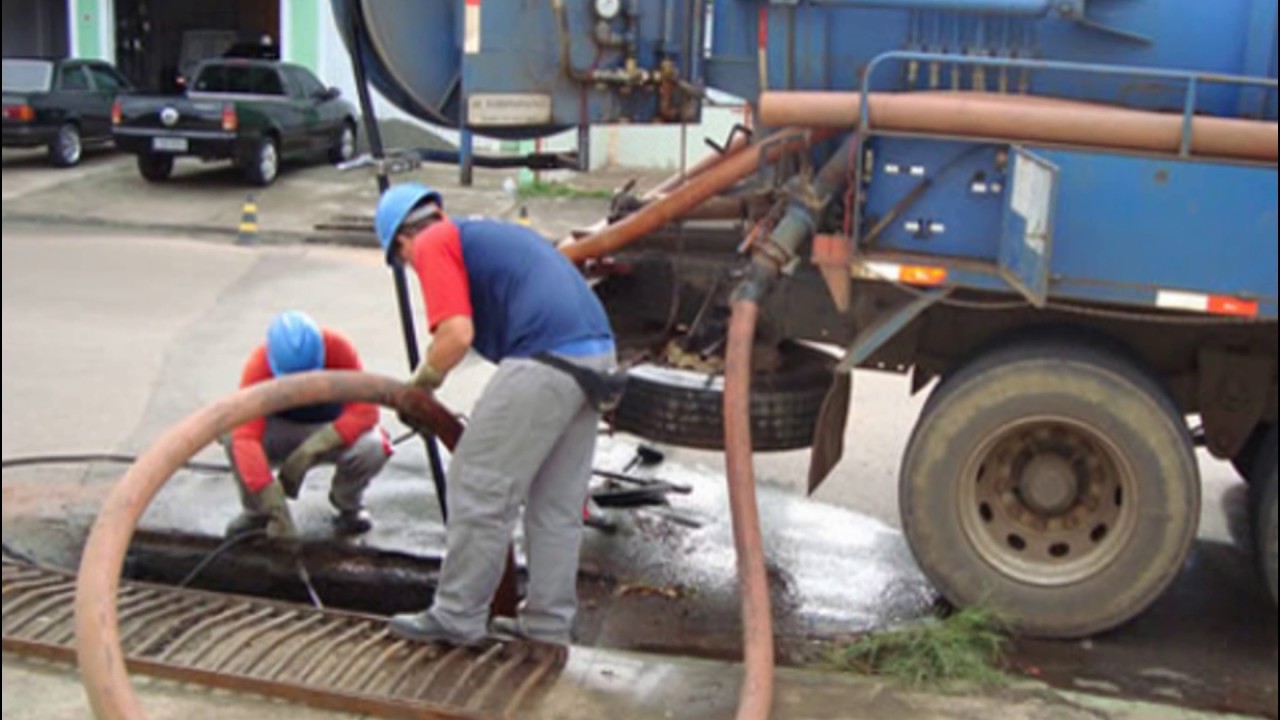 Caminhão com Profissionais desentupidores desentupindo caixa de gordura