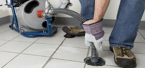 Profissional desentupidor desentupindo ralo com máquina profissional