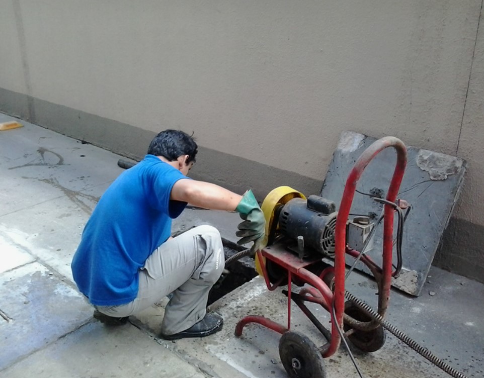 Profissional desentupidor desentupindo esgoto com máquina