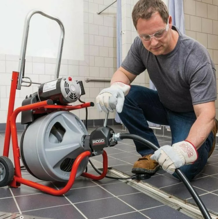 Técnico desentupidor desentupindo ralo com máquina