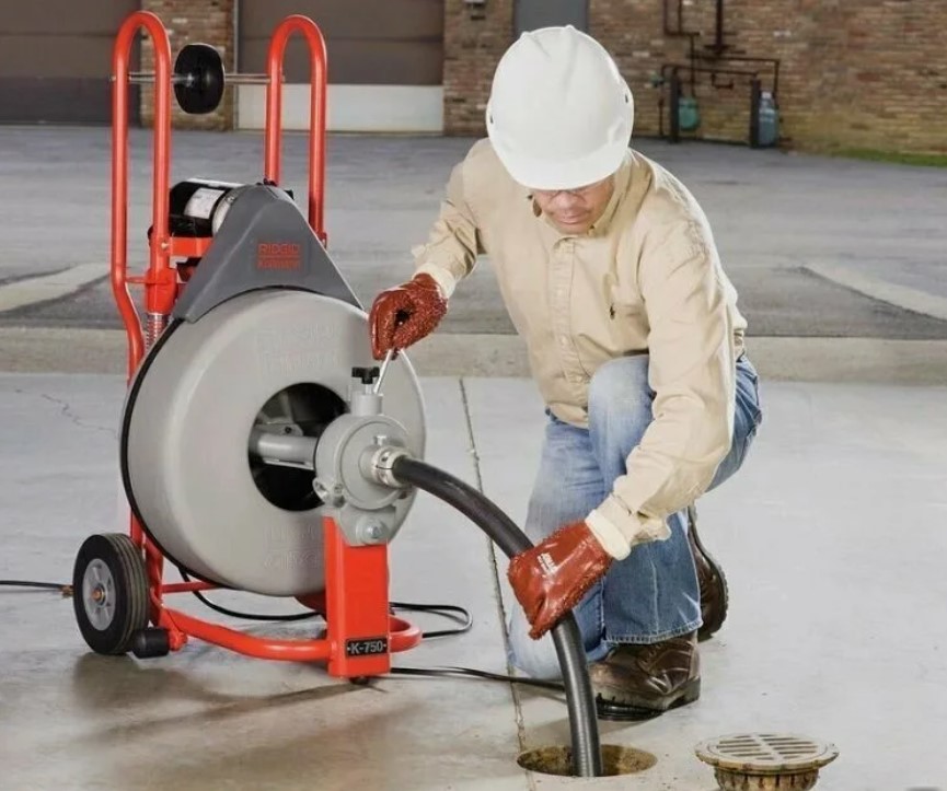 Técnico desentupidor desentupindo ralo externo com máquina