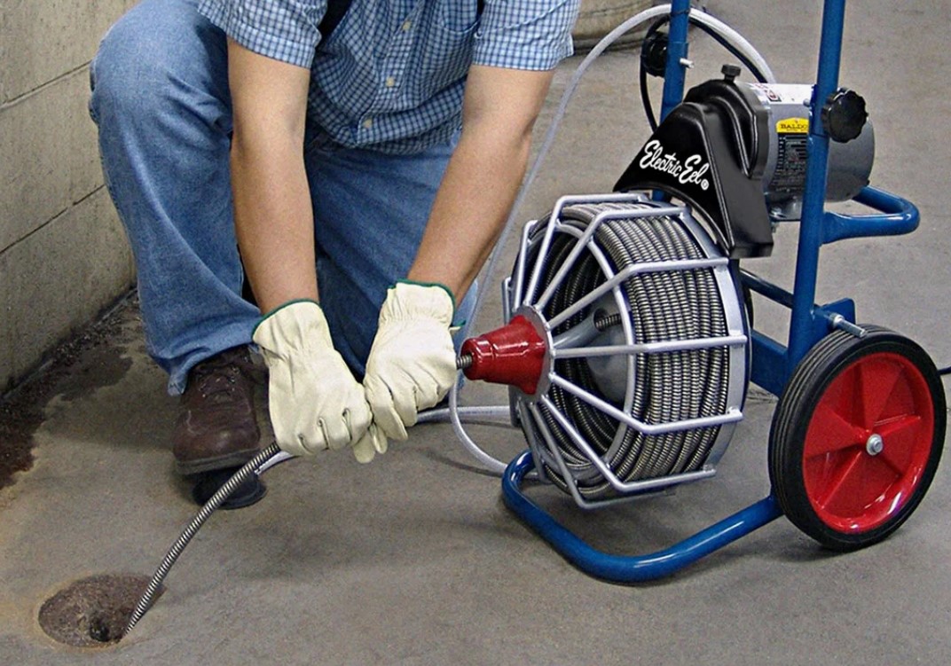 Técnico desentupidor desentupindo ralo com máquina