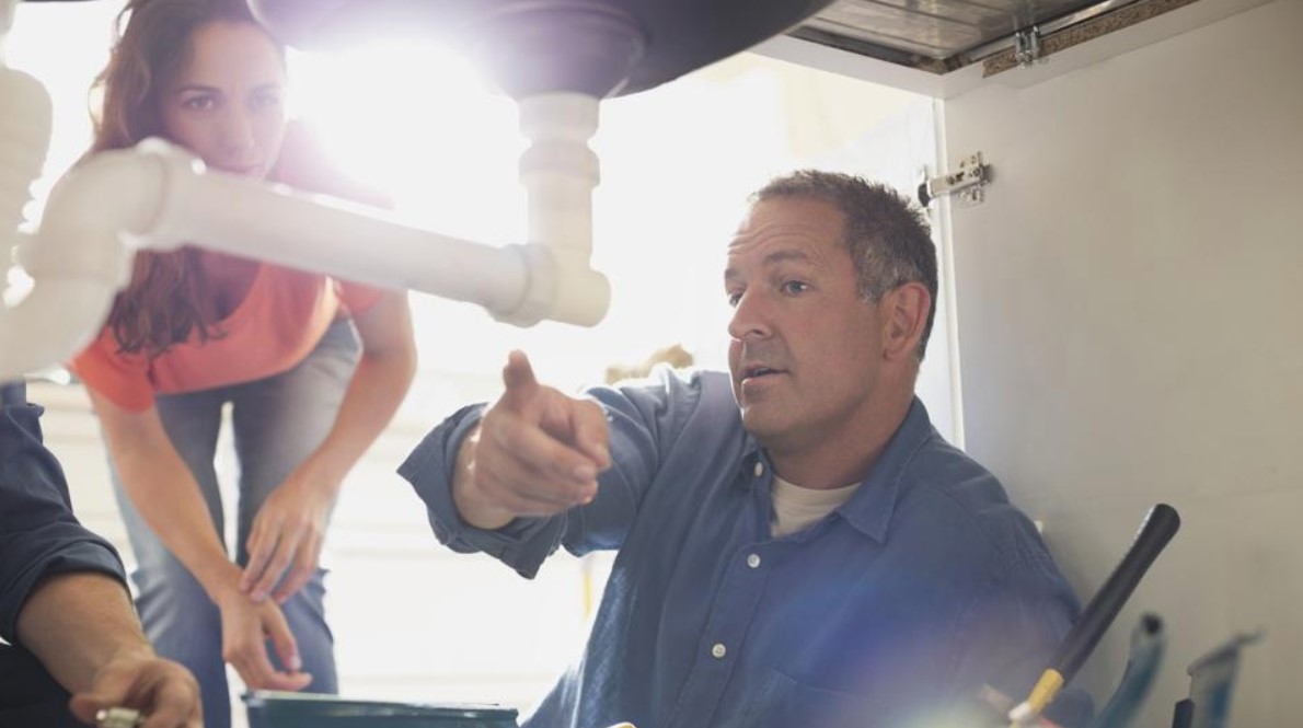 Técnico desentupidor apontando entupimento em uma Pia de cozinha para cliente