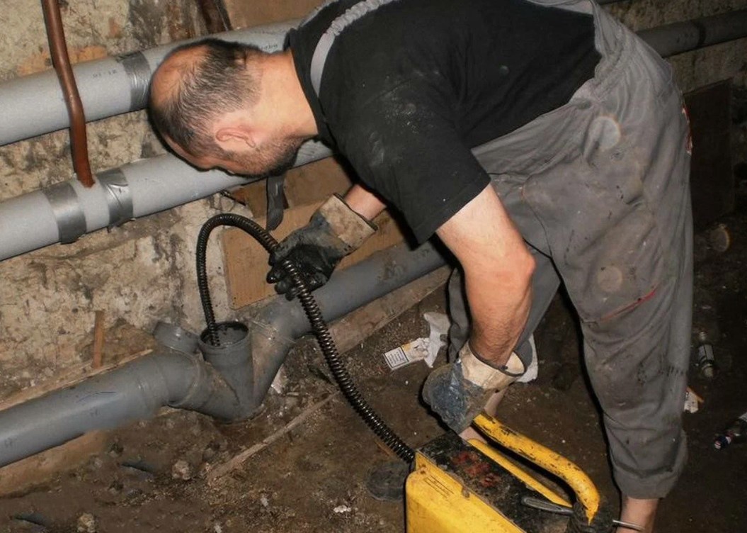 Técnico desentupidor desentupindo cano externo com máquina