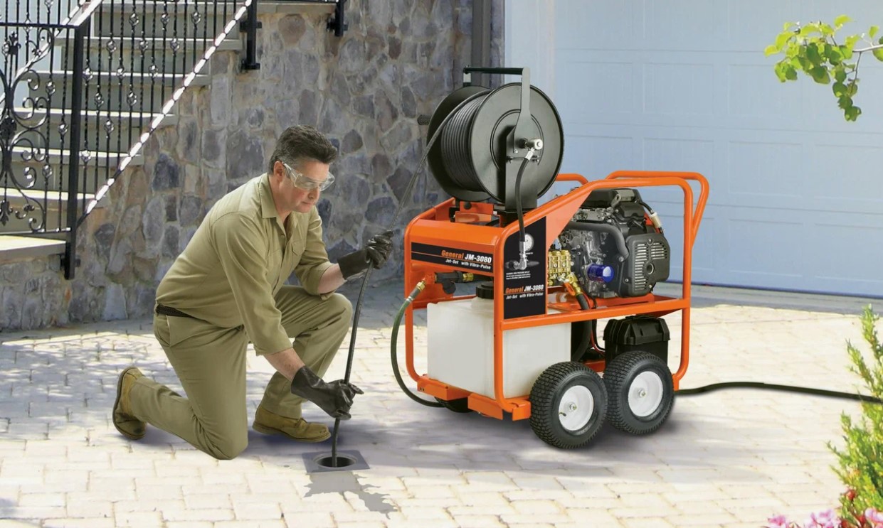 Técnico desentupidor desentupindo ralo externo com máquina