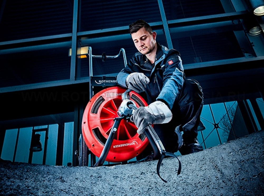 Técnico desentupidor desentupindo esgoto externo com máquina