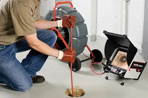 Técnico desentupidor desentupindo esgoto externo com máquina