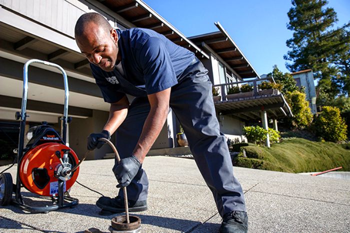 Técnico desentupidor desentupindo ralo externo com máquina