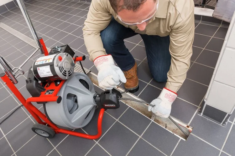 Técnico desentupidor desentupindo ralo externo com máquina